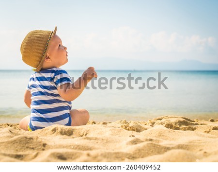 Little baby boy sitting on the sand