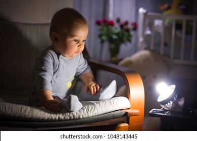 Little Baby Boy, Sitting In Rocking Chair, Looking With Curiousity At A Night Lamp, Dim Light