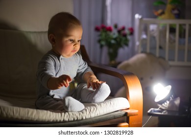 Little Baby Boy, Sitting In Rocking Chair, Looking With Curiousity At A Night Lamp, Dim Light