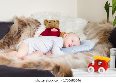 Little baby boy sleeping on a sofa on artificial fur, surrounded by toys - teddy bears and fire truck - Shutterstock ID 1706685646