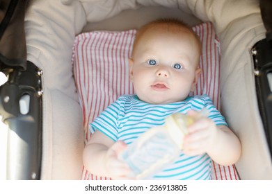 Little baby boy in stroller with bottle of water at summer day