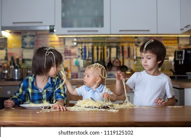 Little Baby Boy, Toddler Child And His Older Brothers, Eating Spaghetti For Lunch And Making A Mess At Home In Kitchen