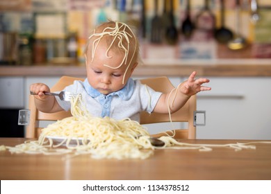 Little Baby Boy, Toddler Child, Eating Spaghetti For Lunch And Making A Mess At Home In Kitchen