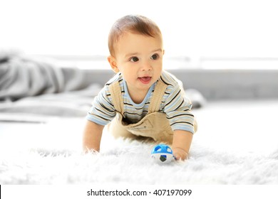 Little baby boy with a toy crawling on the floor at home - Shutterstock ID 407197099