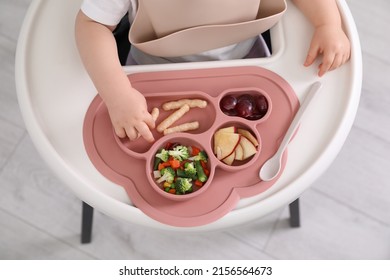 Little Baby Eating Food In High Chair At Kitchen, Closeup. Top View