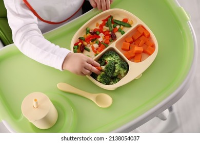 Little baby eating healthy food in high chair, closeup. Above view