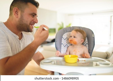 A Little Baby Eating Her Dinner And Making A Mess With Dad On The Side