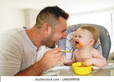 A Little Baby Eating Her Dinner And Making A Mess With Dad On The Side