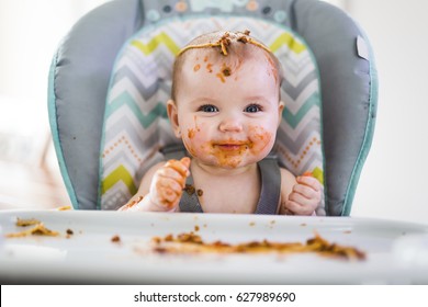 A Little Baby Eating Her Dinner And Making A Mess