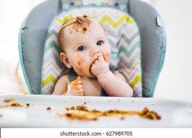 A Little baby eating her dinner and making a mess