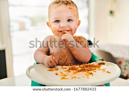 A Little baby eating her dinner and making a mess