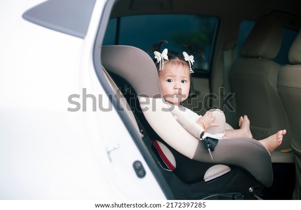 Little baby fastened\
with security belt in safety car seat. Toddler girl buckled into\
her car seat. Adorable little girl sitting in car. Image of safety\
before drive car.