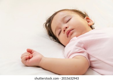 Little Baby Girl 12 Months Wearing Pink Cloth Sleeping On White Bed At Home. Adorable One Year Old Toddler Mixed Race Asleep Having Good Dream Resting In The Bedroom. 