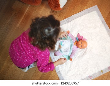 Little Baby Girl Changing Diaper To Her Doll Toy.