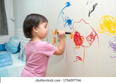  little baby  girl drawing with crayon color on the wall