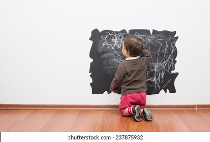Little baby girl drawing on the wall