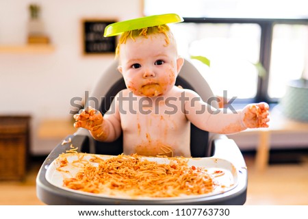 Little baby girl eating her spaghetti dinner and making a mess