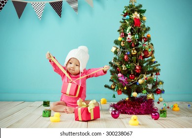 Little baby girl open the gift box with decorating christmas tree on green background in winter season, Baby healthy and winter concept - Powered by Shutterstock