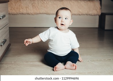 little baby girl sitting on the floor in an interesting and funny pose, happy