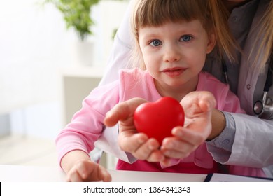 Little baby girl visiting doctor holding in hands red toy heart as life safe symbol - Shutterstock ID 1364341343