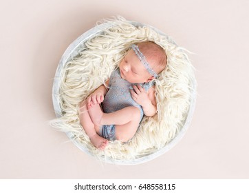 Little baby in gray suit sleeping and moving her legs in sleep on pillow, topview