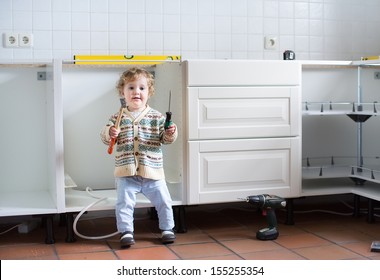 Little baby helping to assemble a kitchen in a new home - Powered by Shutterstock