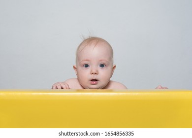 Little Baby Look Out. Peek A Boo. Child Looks Out From Behind Table