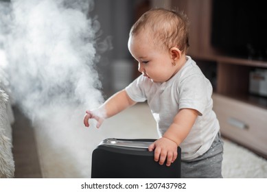 Little baby looks at the humidifier. Moisture in the house concept