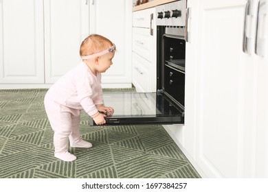 Little Baby Near Stove In Kitchen. Child In Danger