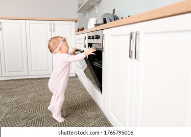 Little baby near stove in kitchen. Child in danger