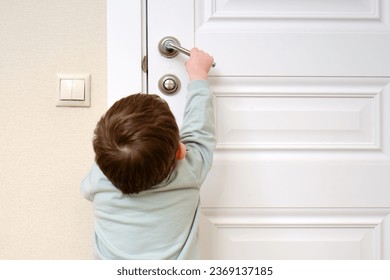 Little baby opens the door. Child pulls the door handle with the lock closed. Kid aged two years - Powered by Shutterstock