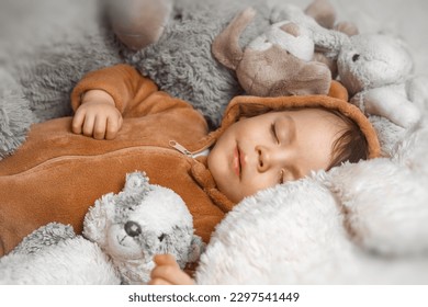 Little baby with outstretched hands lying in bed with fluffy stuffed toys of animals. Toddler sleeping with teddy bear in cozy room and enjoy healthy night sleep. Selective focus. High quality photo - Powered by Shutterstock