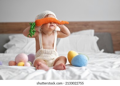 Little baby in rabbit costume covering eyes with big carrot   - Shutterstock ID 2133022755