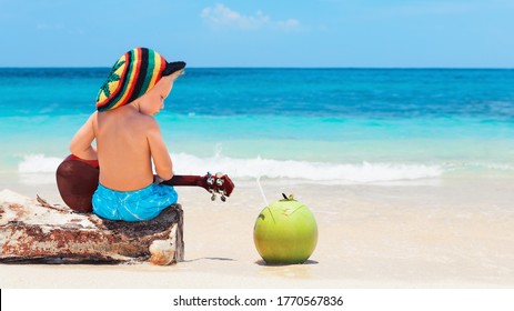 Little Baby In Rasta Hat Play Reggae Music On Hawaiian Ukulele, Enjoy Relaxing On Ocean Beach. Kids Healthy Lifestyle. Family Summer Holiday. Activity On Tropical Jamaica And Caribbean Island Travel.