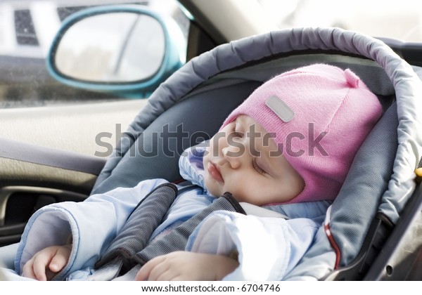 Little baby\
sleeping in a car in a child`s car\
seat