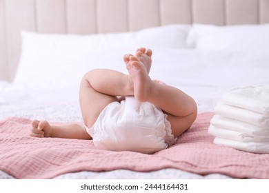 Little baby and stack of diapers on bed, closeup