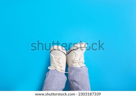 Little baby in stylish gumshoes on light blue background, top view. Space for text