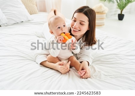 Little baby baby toddler infant newborn baby nibbles on a toy butterfly. Teething process, baby teeth concept. Playing games with a child. Child care and motherhood.