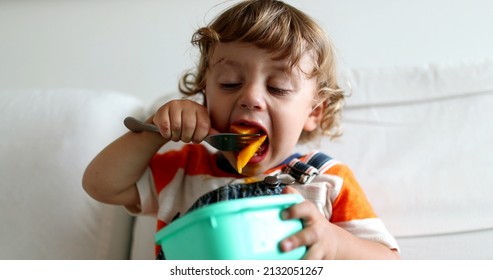 Little Baby Toddler Sitting On Sofa Eating Fruit With Fork