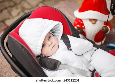 Little Baby Toddler In White Winter Clothes Sitting In Car Seat. On Cold Winter Day. Children Safety In Car Concept.