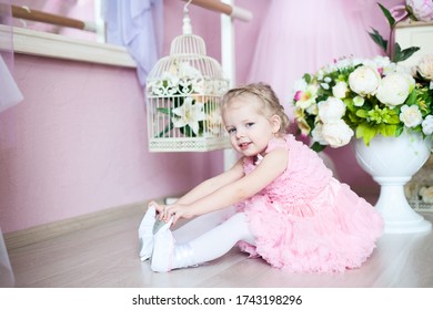 A Little Ballerina In A Dress Sits In A Dance Class On The Floor. Near A Bouquet Of Flowers.