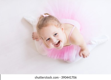 Little Ballerina Girl In A Pink Tutu. Cute Child Dancing Classical Ballet In White Studio. Children Dance. Young Dancer In A Class. Preschool Kid Sitting On Hardwood Floor. Copy Space For Your Text.