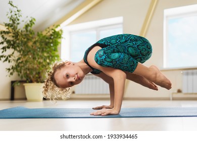 Little beautiful blonde girl practicing yoga in the studio, doing handstand exercise, kakasana or crow pose on a gymnastic rug. - Powered by Shutterstock