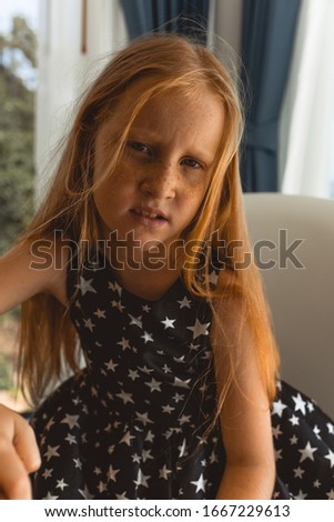 Little beautiful and fashionable girl with red hair and freckles posing in front of the camera. Children's fashion