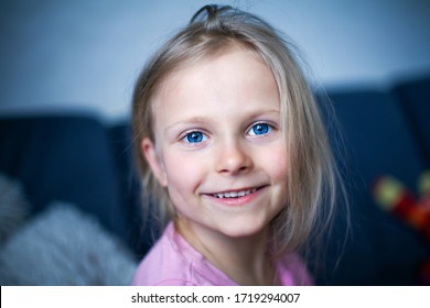 Little Beautiful Girl With Bright Blue Eyes Smiles And Looks At The Camera. Happy Child 6-7 Years Old. Head Close Up