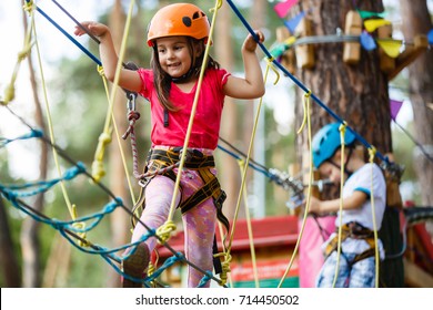 Little beautiful girl climbs on rope harness in summer city park. - Powered by Shutterstock
