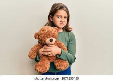 Little Beautiful Girl Hugging Teddy Bear Clueless And Confused Expression. Doubt Concept. 