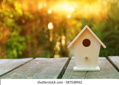 Little Birdhouse over wooden table outdoors in the garden