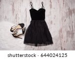 Little black dress and black shoes. Wooden background, fashionable concept