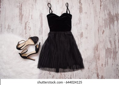 Little black dress and black shoes. Wooden background, fashionable concept